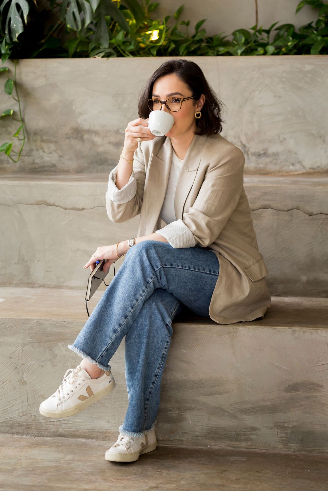 Gabriela Affonso tomando café, sentada em uma escada de cimento